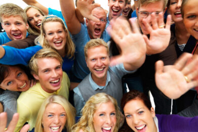 happy men and women with hands raised