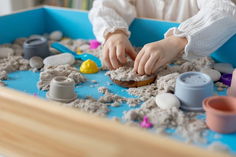 Child playing with sand and toys in a therapeutic sand tray